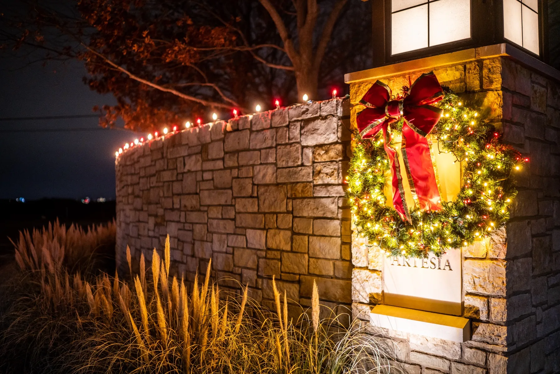 Holiday lighting on a community monument entrance with illuminated wreath