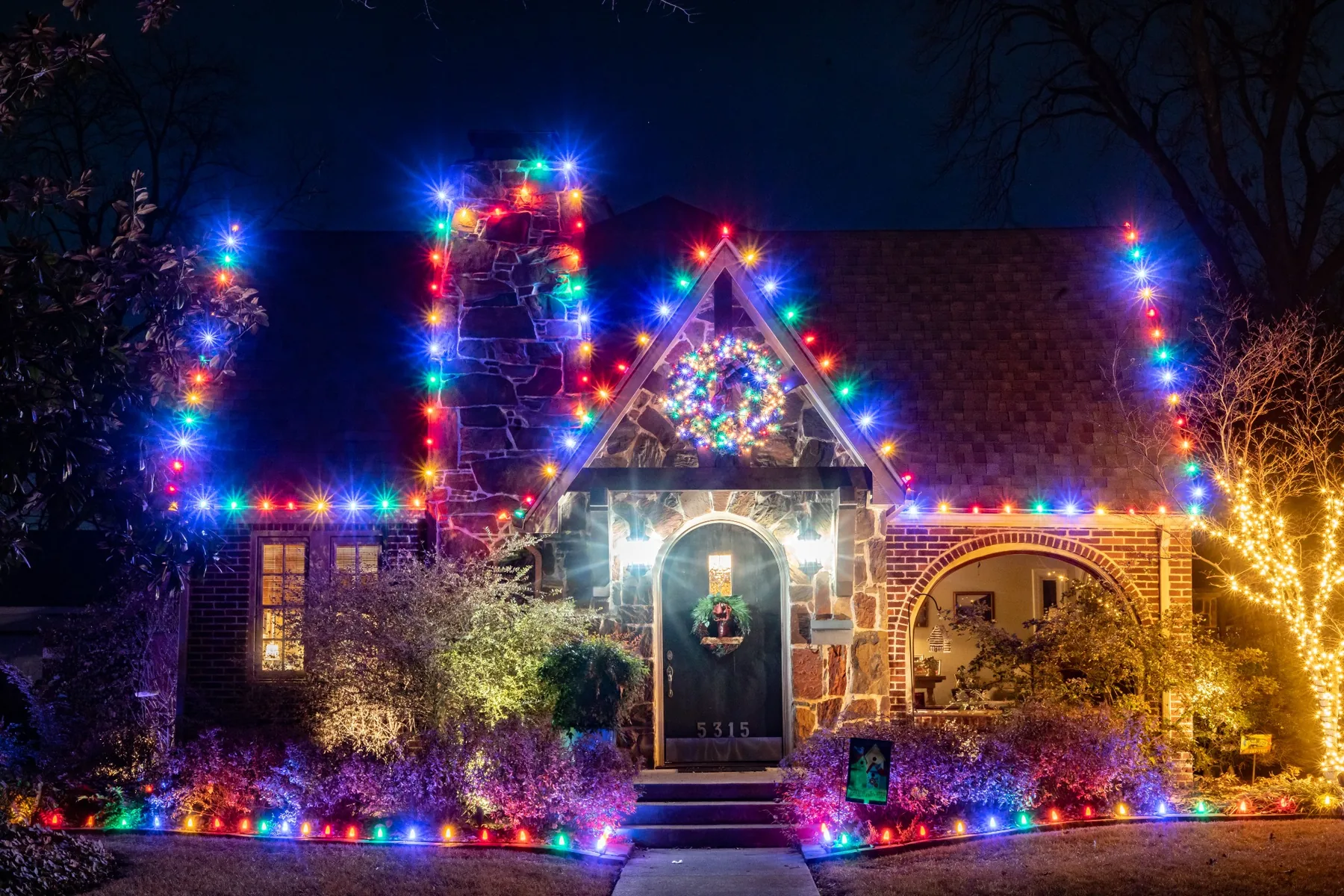 Multicolor C9 roofline and landscape holiday lighting on a residence